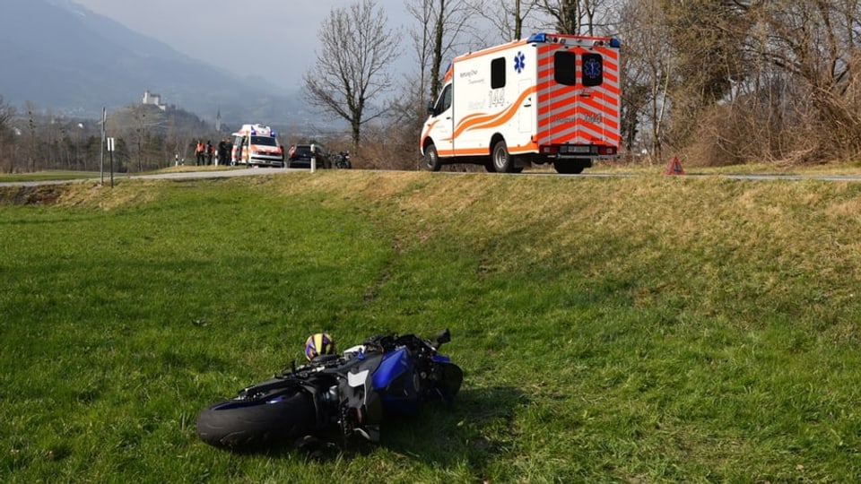 purtret dal töff che giascha en il prà. Sin via èn da vesair las ambulanzas e la polizia.