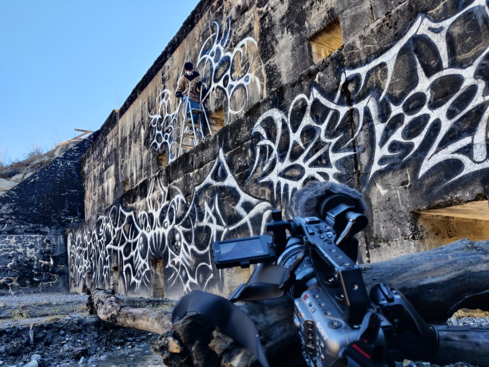 Kamera vor Graffiti-Wand mit Protagonist