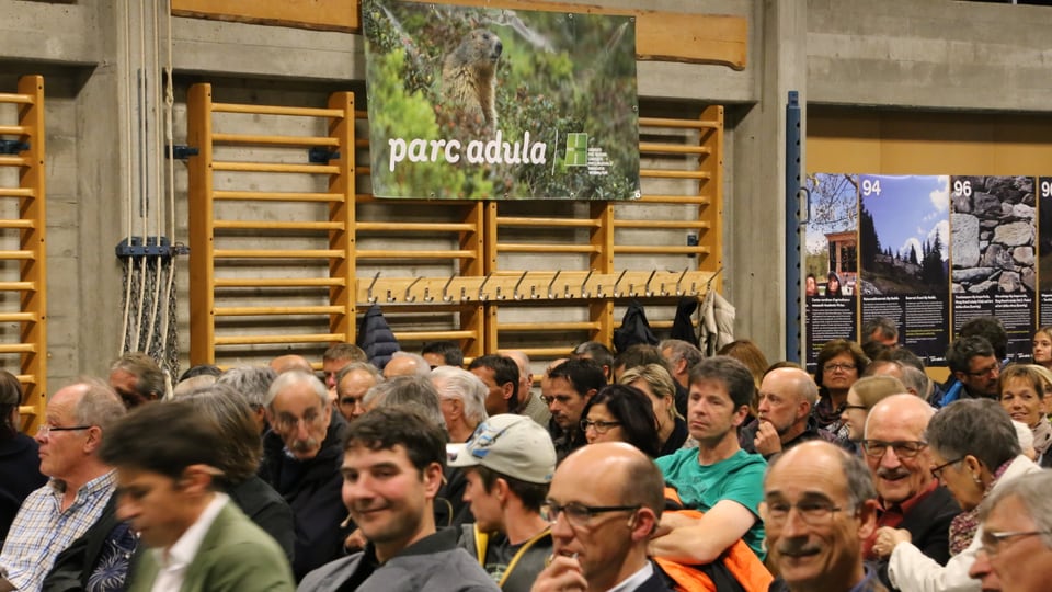 La sala da gimnastica plain glieud vit la preit pendan placats da reclama per il Parc Adula