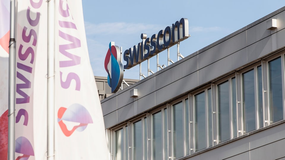 Vista sin il bajetg da la Swisscom. Logo da la Swisscom sin il tetg dal bajetg. Davanttiers bandieras cun si il logo.
