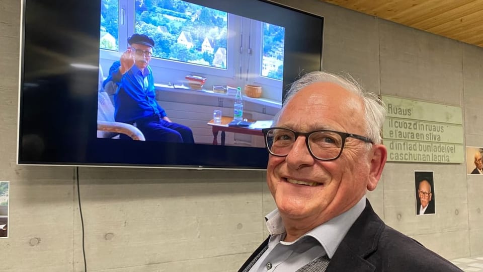 Davant Arnold Spescha, e davos ella televisiun Vic Hendry che auza il maun per salidar.
