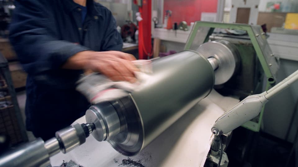 Persuna nettegia la surfatscha d'ina rolla da metal.