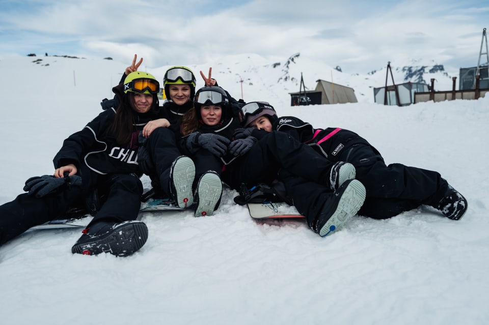 Spass in den Gesichtern, vier Mädchen vom Chill Programm hocken im Schnee und lachen in die Kamera