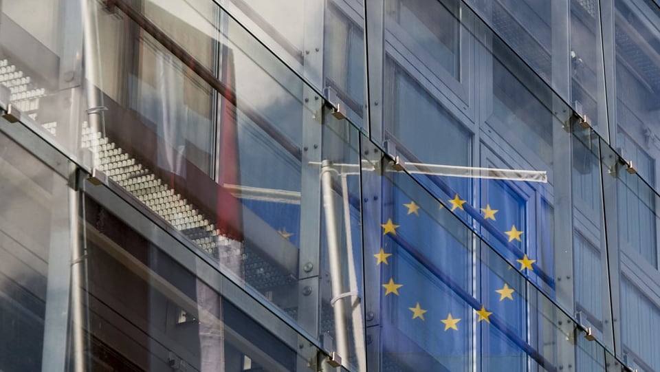 Bandieras da Svizra ed EU che reflecteschan en il vaider d'in bajetg.