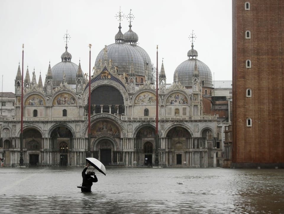 Sin la plazza da Marcus a Venezia emprova in fotograf da fotografar la renumada baselgia. El stat fin tar la taglia en l'aua. 