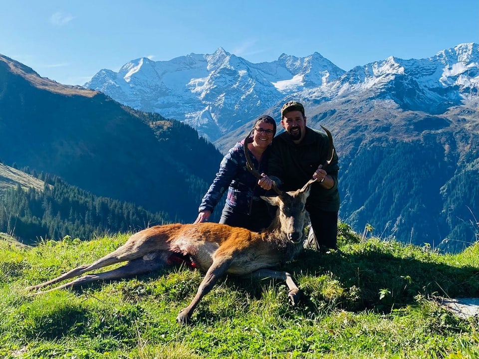 Zwei Personen mit einem geschossenen Hirsch.