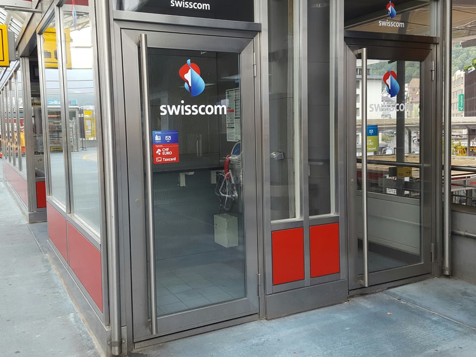 Duas gabinas da telefon cun eschs da glas cun si il logo da la Swisscom.
