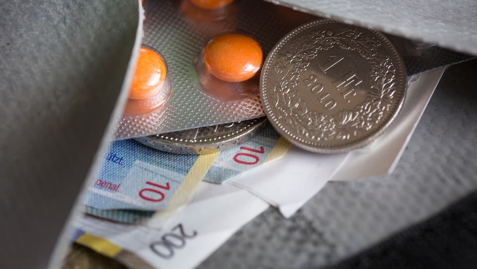 Ina bursa cun tablettas e notas da 200 francs.