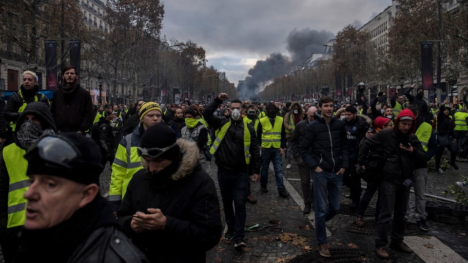 Purtret dals «Gilets jaunes» che van per las vias. 