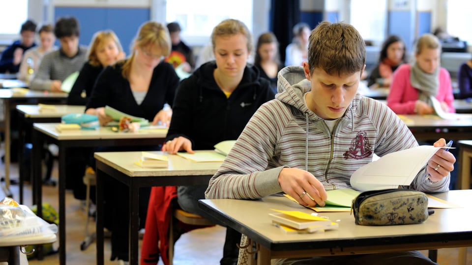 Scolaras ed scolars vid il far l'examen d'admissiun. 