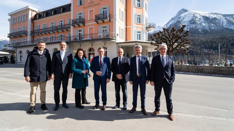 Pliras persunas stattan en retscha avant il Hotel Belvedere a Scuol.