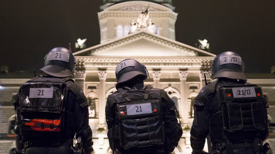 polizists en mondura e chapellinas avant chasa federala