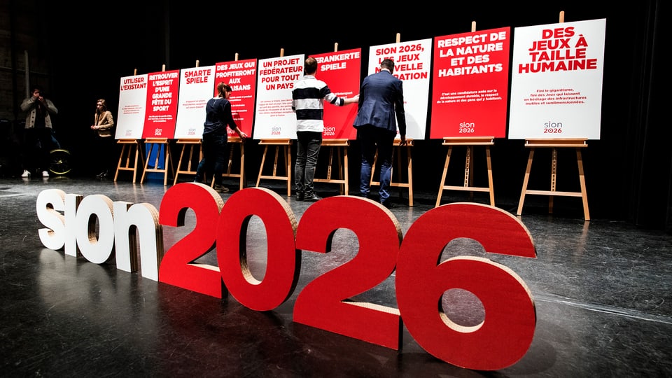 Gustabs sion 2026 sin ina tribuna cun placats per ils gieus davostiers.