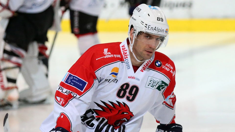 Il giugader da hockey sin glatsch Roman Botta en il dress alv-cotschen cun il numer 89 e chapellina alva. 