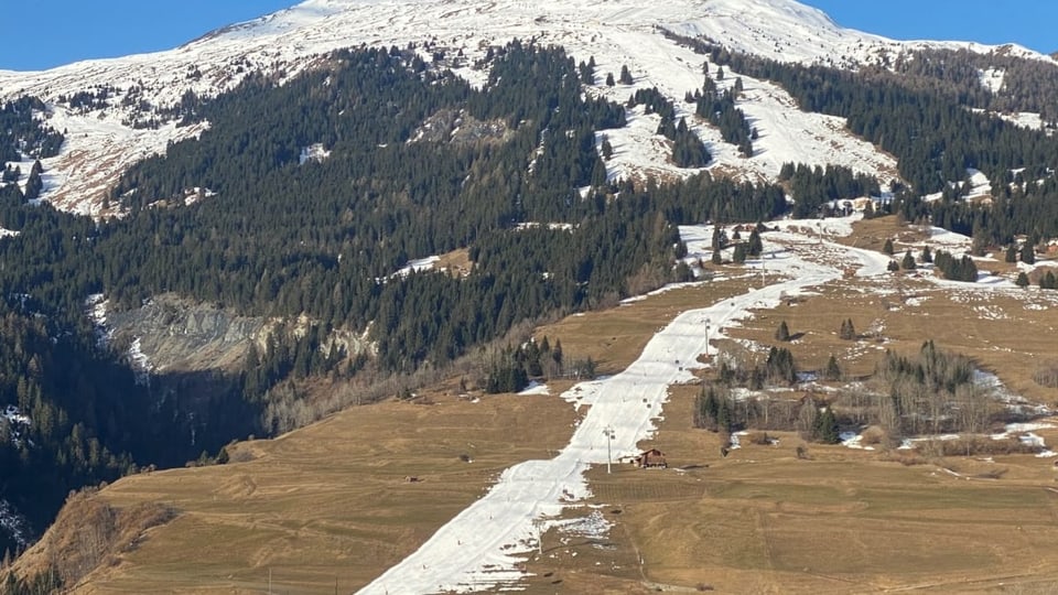 Eine Piste in Savognin, daneben braune, schneefreie Wiesen