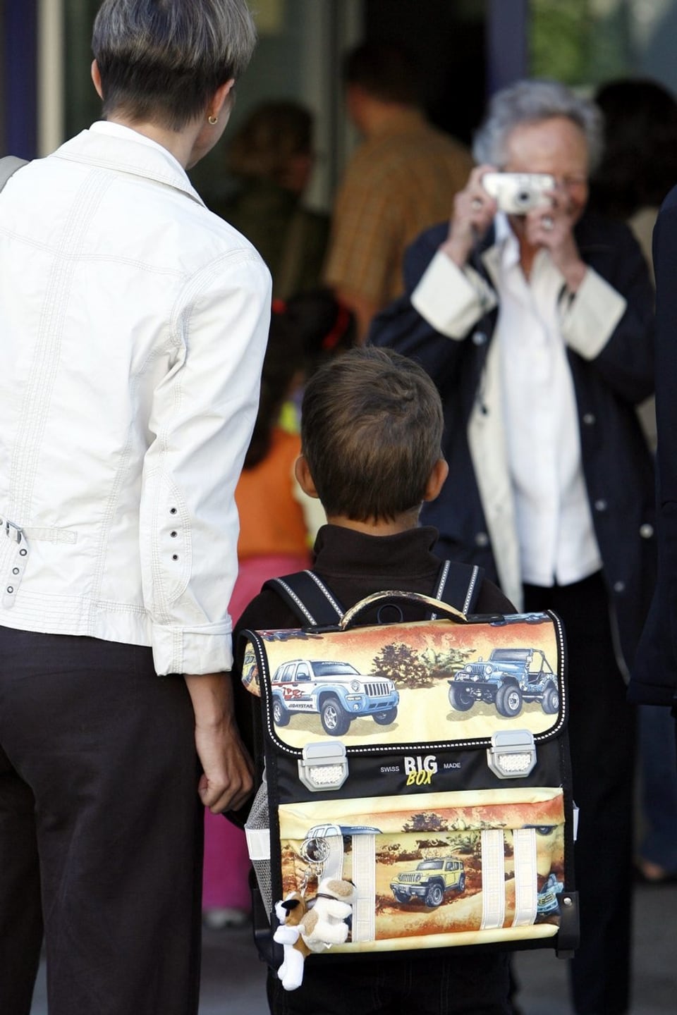 Nona che fotografescha uffant cun mamma a l'emprim di da scola