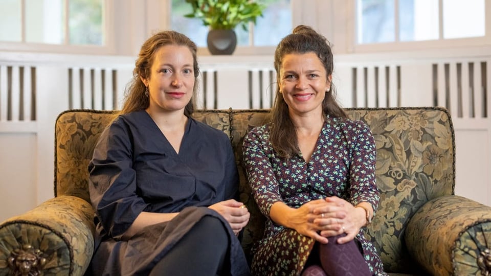Bettina Vital und Flurina Badel nebeinander auf einem Sofa.