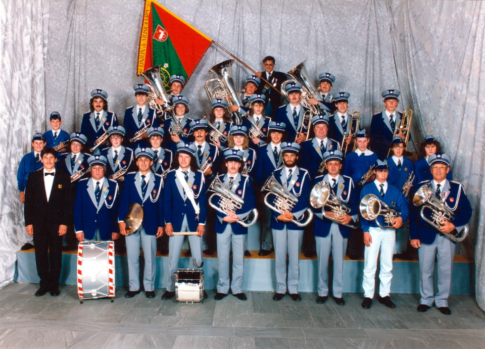 Musikgesellschaft Vrin posiert für ein Vereinfoto in der blau/grauen Uniform.