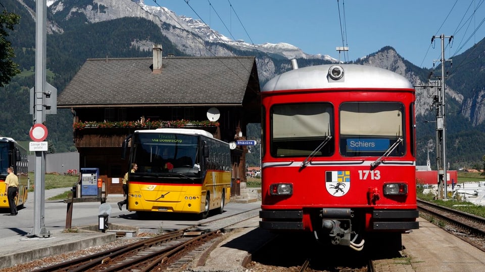 Purtret d'in auto da posta ed ina locomotiva da la Retica. 