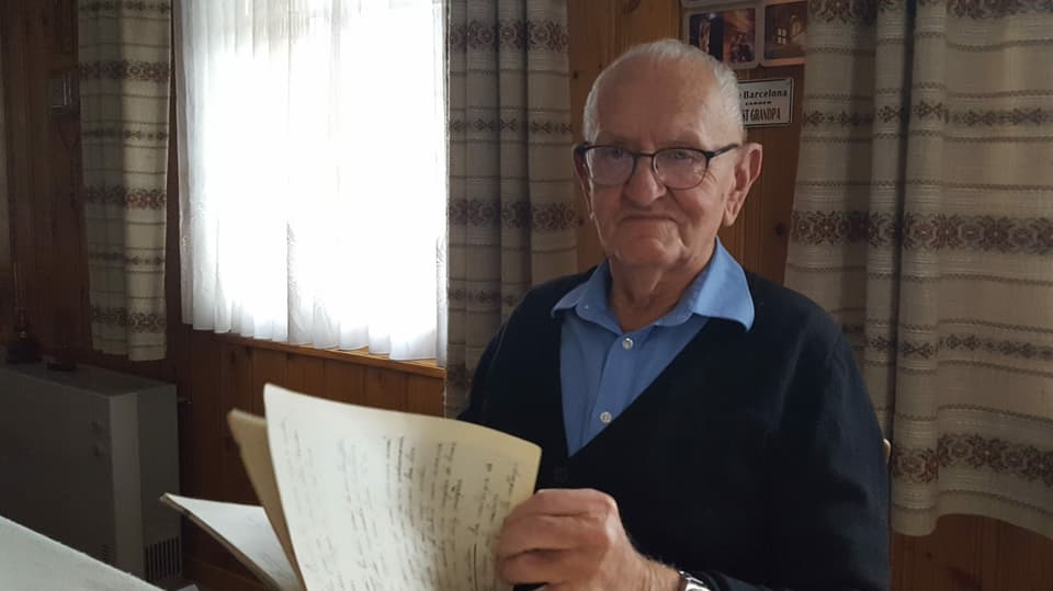 Purtret da Pius Bundi che sfeglia en in cudesch grond cun datas veglias da fieras. 