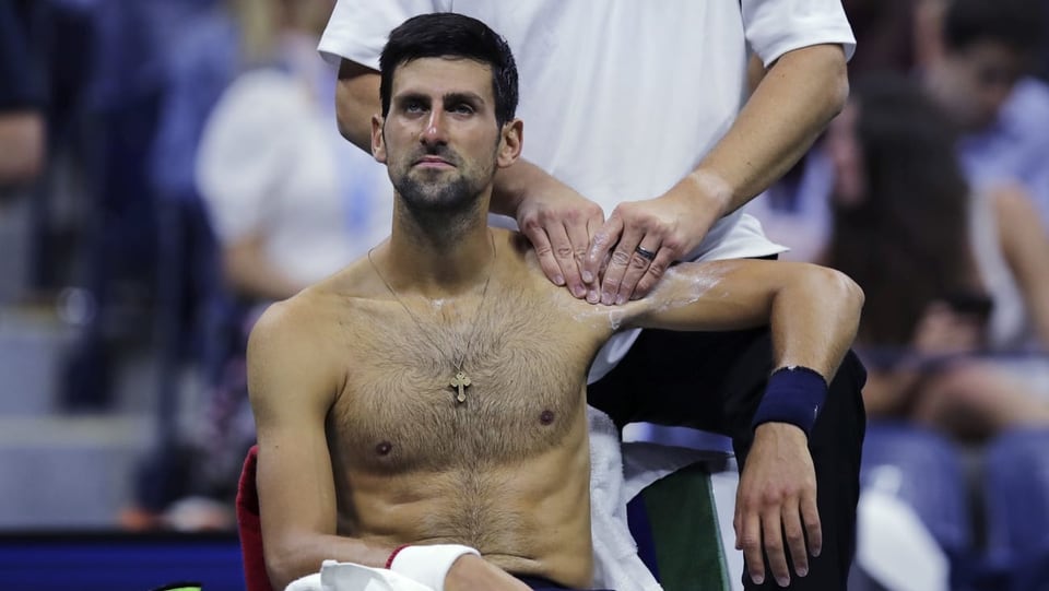 Purtret da Djokovic che sesa e lascha far massascha vi da sia spatla sanestra. 
