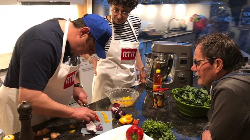 Sergio Guetg schneidet Zwiebel, Simona e Sep Hendry schauen zu.