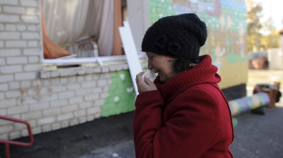 Ina dunna davant ina scolina destruida. 