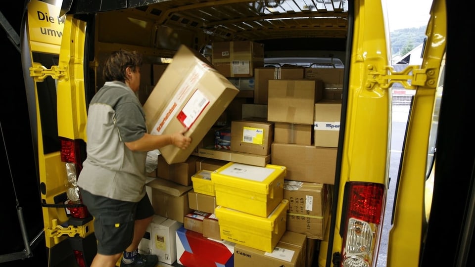 Ina curriera da pachets davant l'auto emplenì cun pachets.