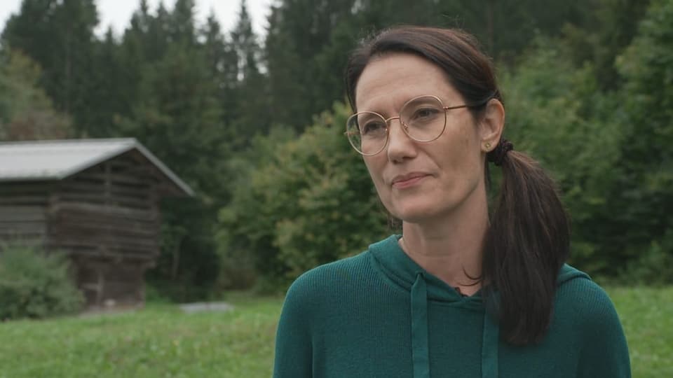 Nathalie Brady Dunna cun pulover verd. Davor in prau, pumers ed in clavau.
