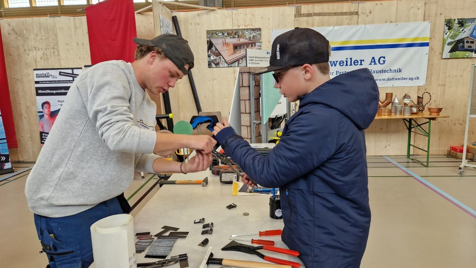 Ein Schüler und ein Sanitärlehrling arbeiten gemeinsam über einen Tisch gebäugt.