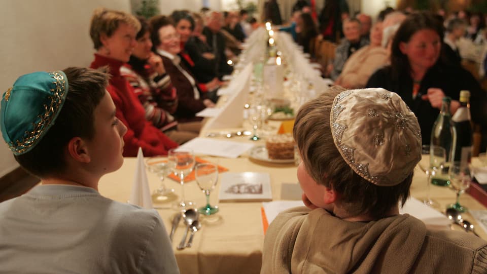 Gidieus durant ina festa tradiziunala enturn ina gronda maisa. Dus mats portan ina kippa. 