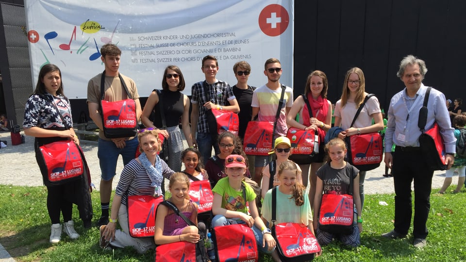 Jugendensemble Singschule Chur Purtret dals uffants e dirigents davant ina reclama per il festival.
