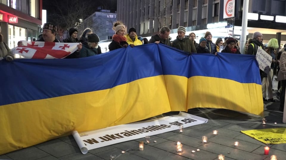 Persunas che tegnan ina bandiera da l'Ucraina.