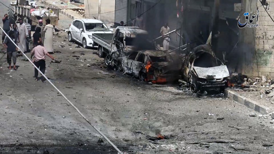 Autos ch'ardan e persunas che van per las vias enturn. 