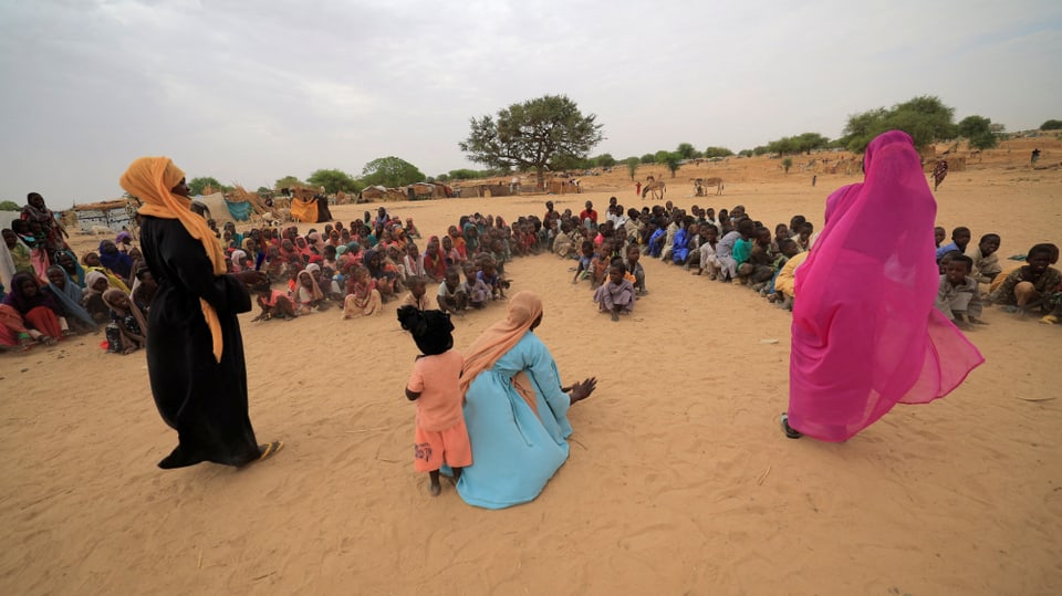 Ina scolasta ed uffants cuntinueschan cun l'instrucziun da scola. Els èn fugids da la guerra en il Sudan.